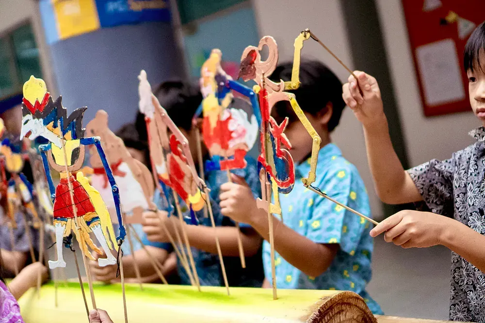 A group of children are playing with paper puppets.