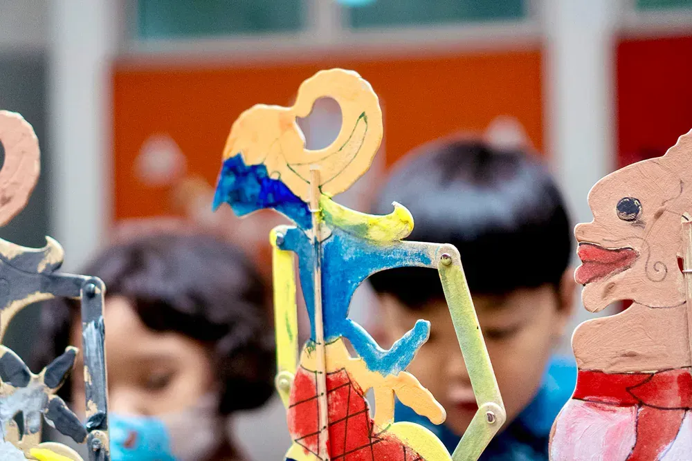 A group of children are looking at a display of handmade puppets.
