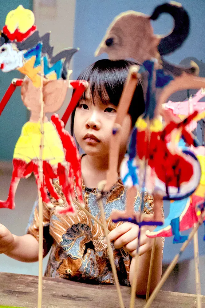A little girl is playing with paper puppets on sticks