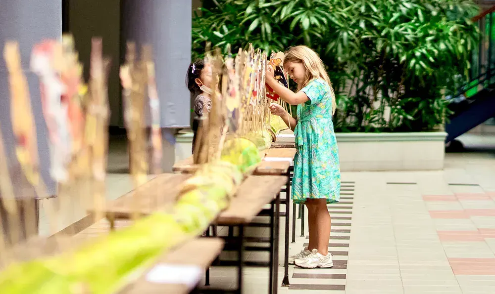 A little girl is standing in front of a table with a bunch of sticks on it.