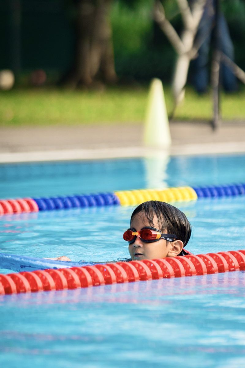 A young boy wearing goggles is swimming in a swimming pool.