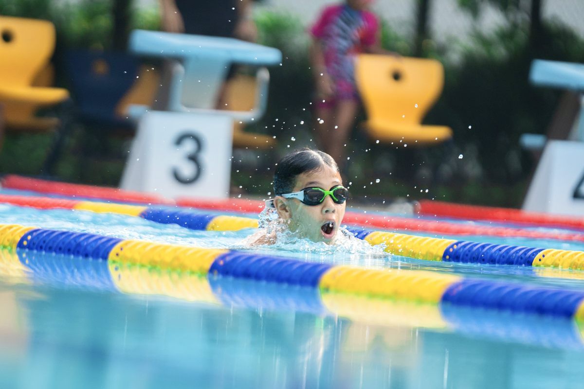 A young girl is swimming in a swimming pool wearing goggles.