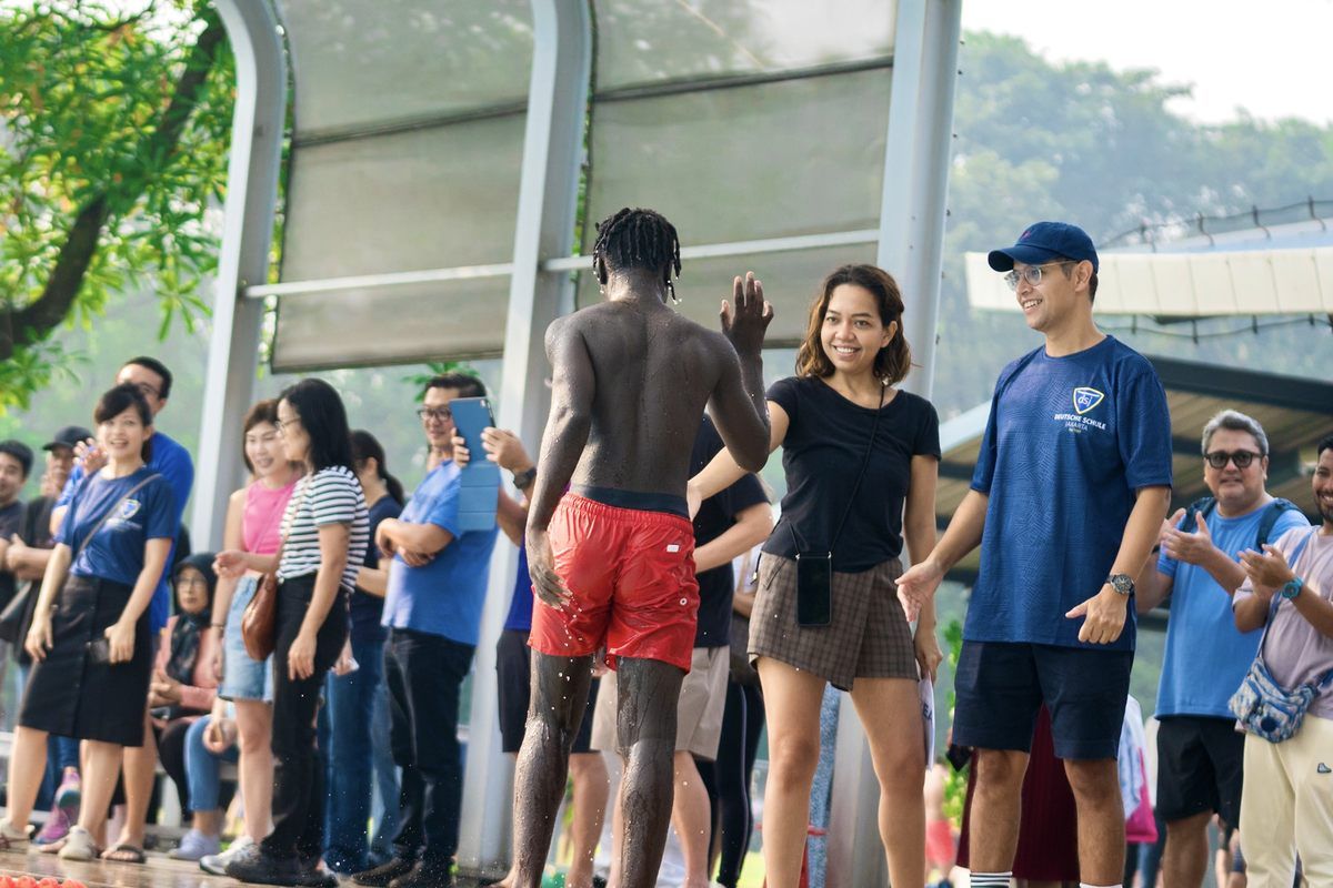 A man in red shorts is standing in front of a crowd of people.