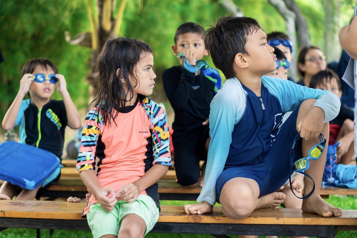 A group of children are sitting on a wooden bench.