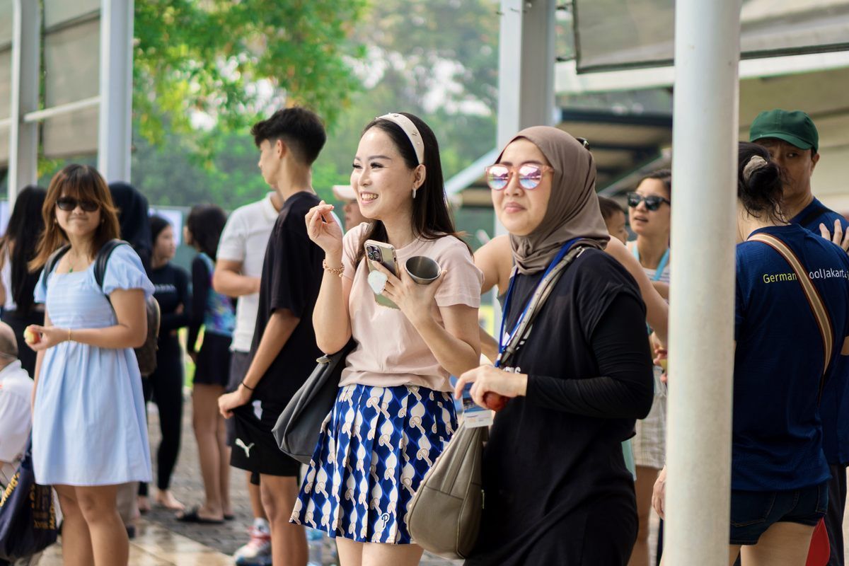 A group of people are standing in a line at a bus stop.