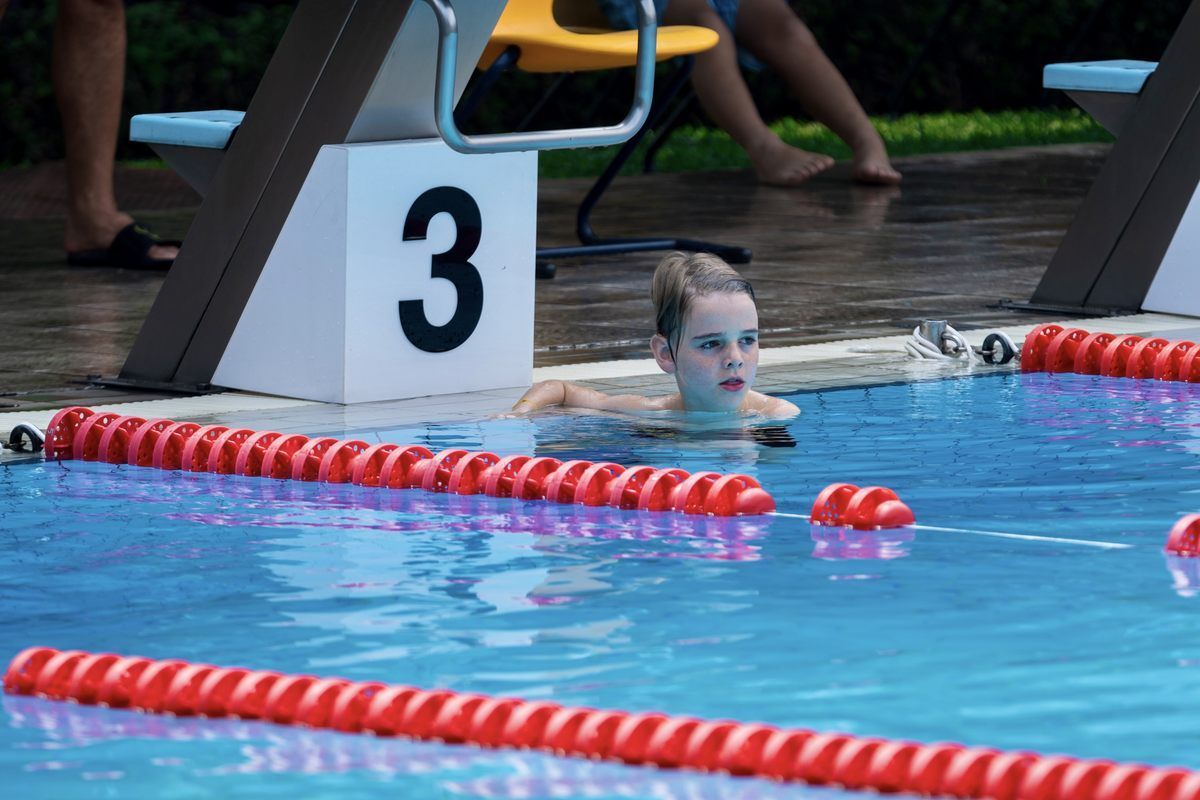 A woman is swimming in a pool with a number 3 block in the background