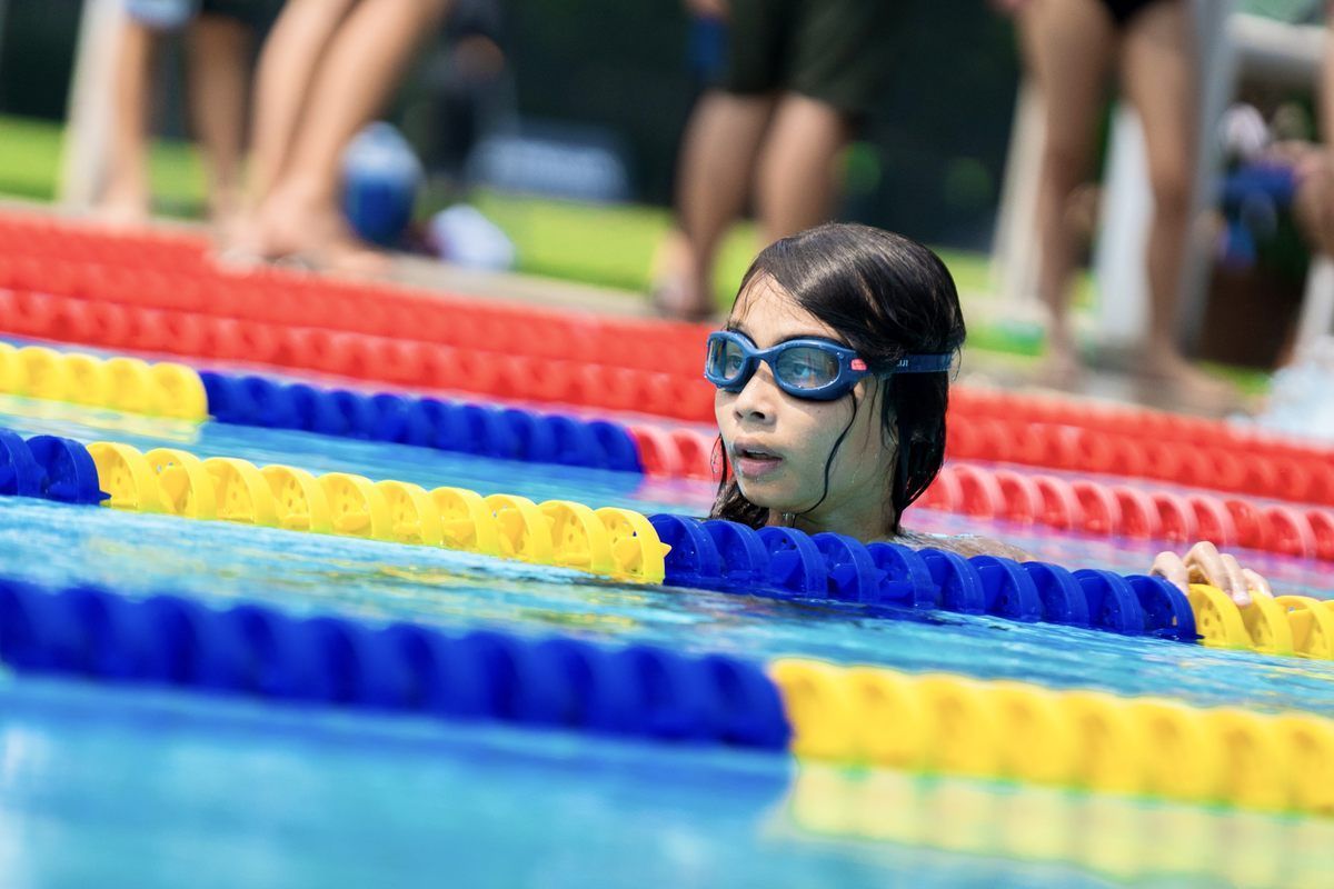 A young girl is swimming in a pool wearing goggles.