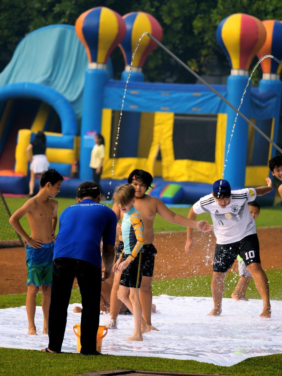 A group of kids are playing in a field with a bouncy house in the background