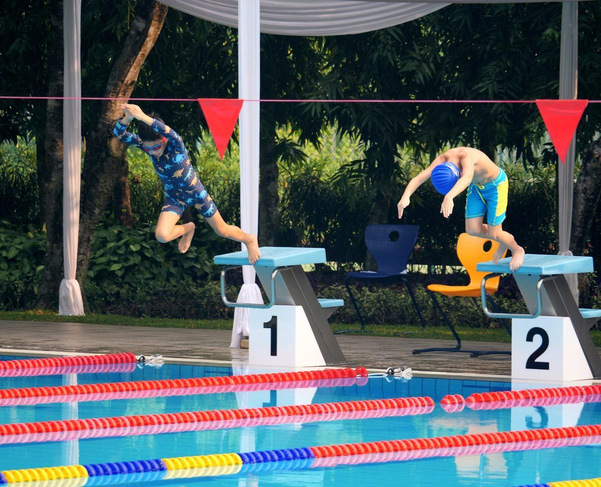 Two boys are jumping into a swimming pool with blocks 1 and 2 in the background