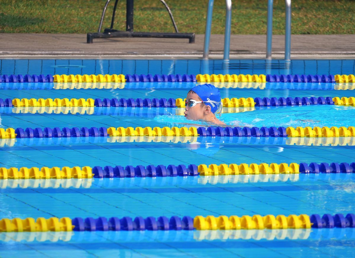 A person is swimming in a pool with blue and yellow lanes
