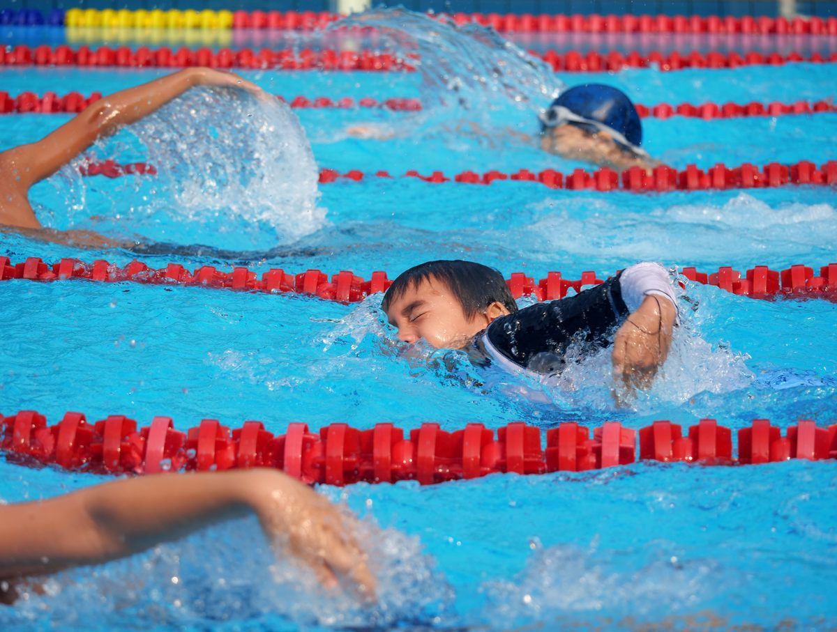 A group of people are swimming in a pool with red lanes.