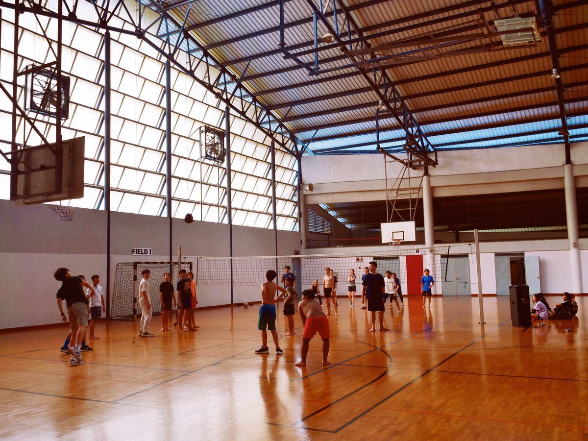 A group of people are playing volleyball in a gym