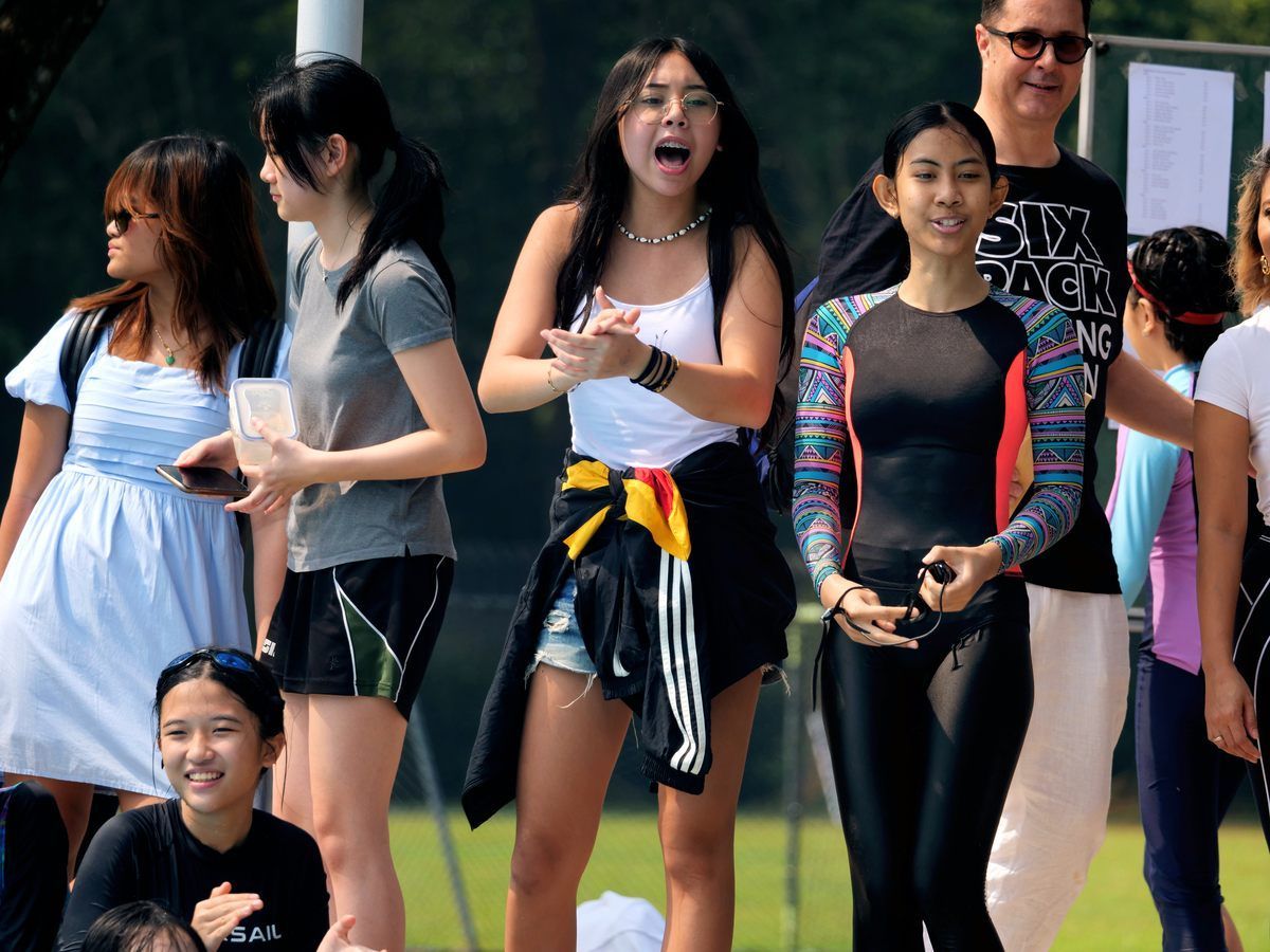 A group of people standing in a line with one wearing a shirt that says super duck