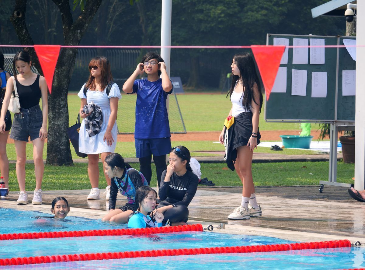 A group of people are standing around a swimming pool.
