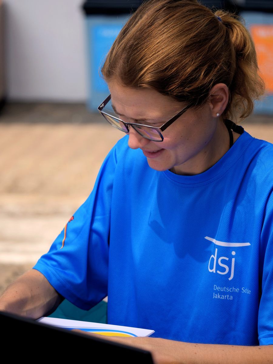 A woman wearing glasses and a blue shirt that says dsj