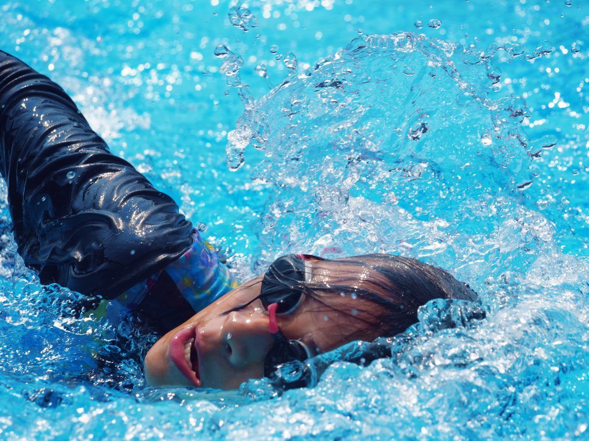 A woman wearing goggles is swimming in a pool.