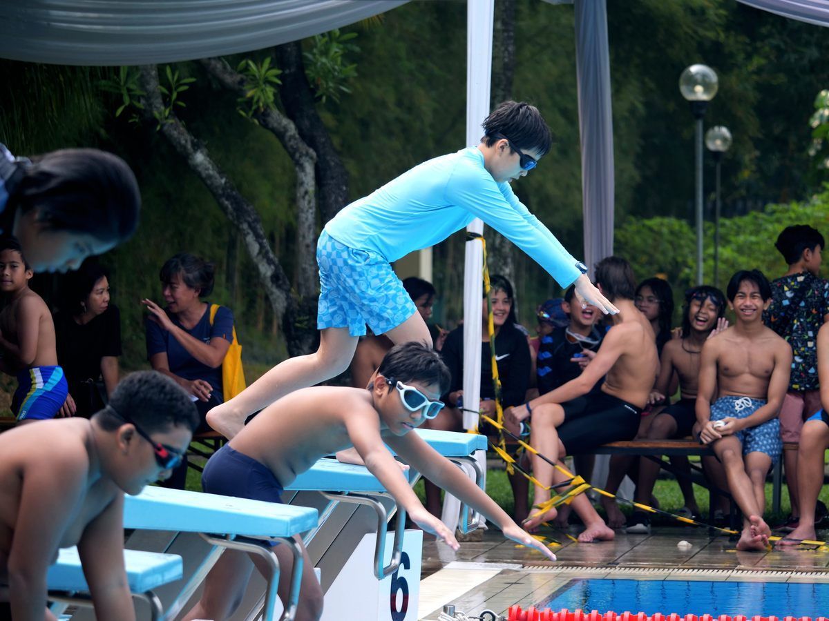 A boy in a blue shirt is jumping into a pool