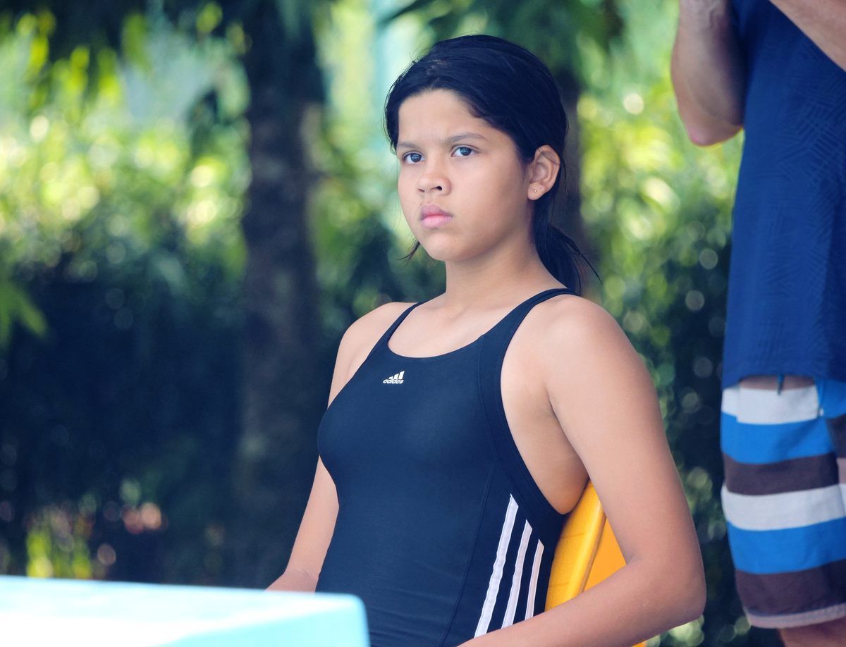A young girl in a black adidas swimsuit