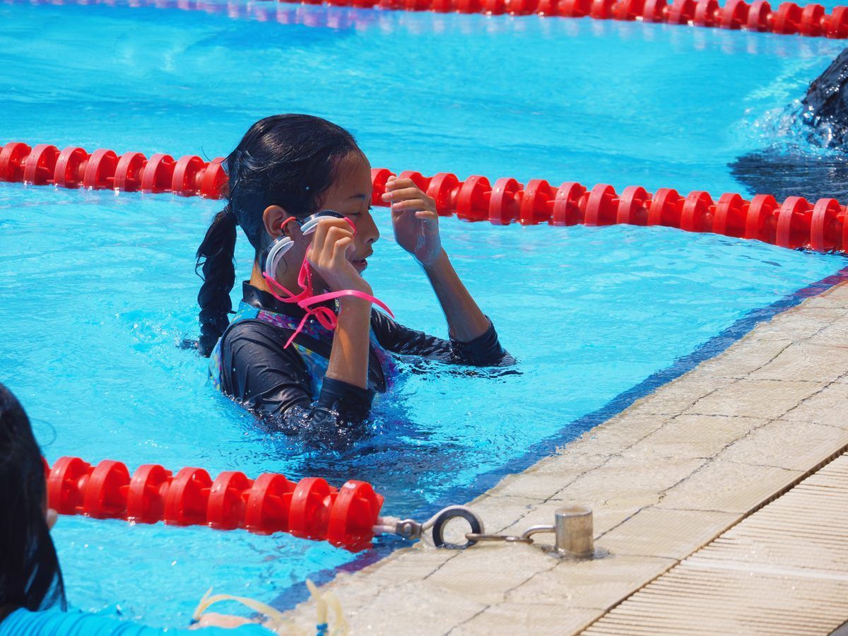 A young girl is swimming in a pool with red lanes.