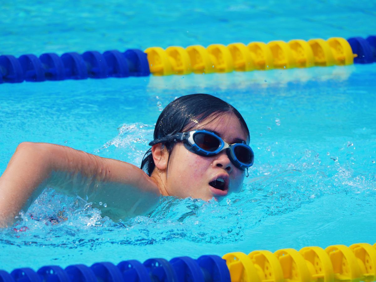 A woman wearing goggles is swimming in a pool.
