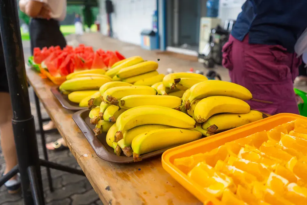 A table topped with trays of bananas and watermelon slices.