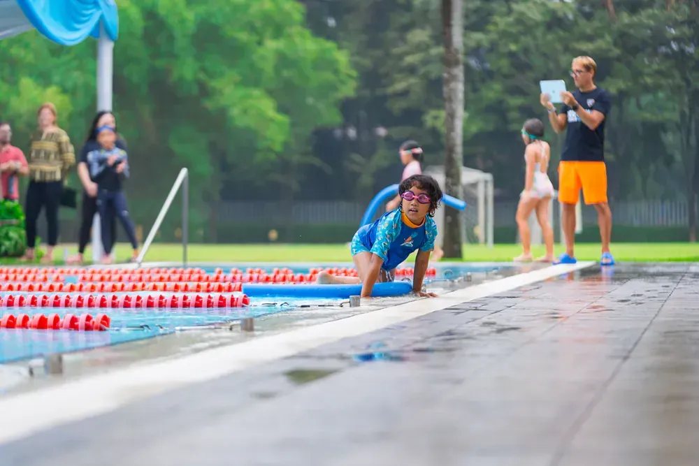 A young girl is crawling into a swimming pool.