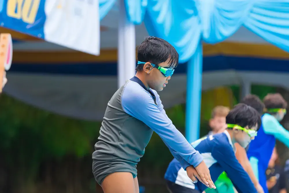 A group of young boys are getting ready to swim in a pool.