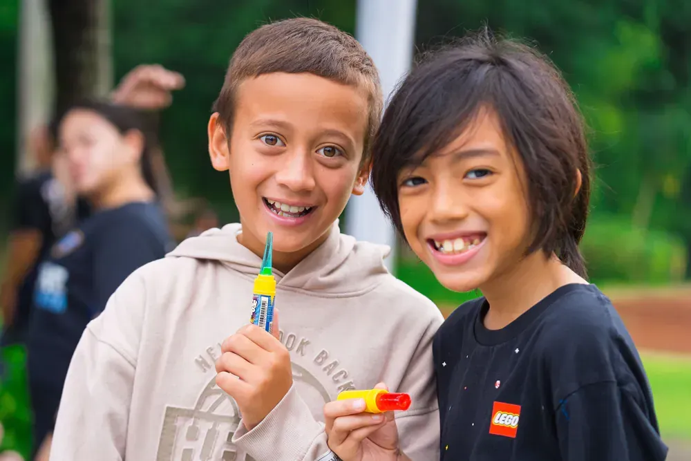 Two young boys are standing next to each other and smiling for the camera.
