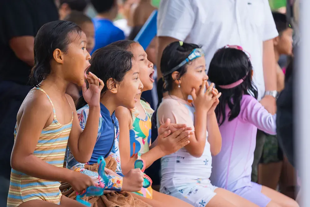 A group of young girls are sitting next to each other and clapping their hands.