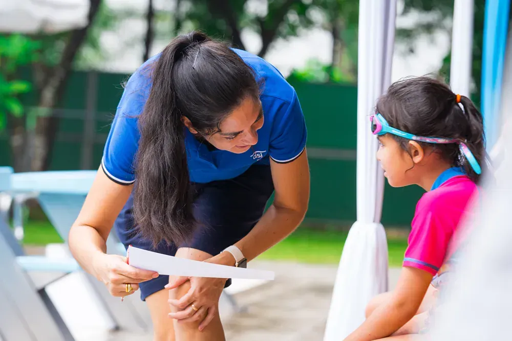 A woman is talking to a little girl while holding a piece of paper.