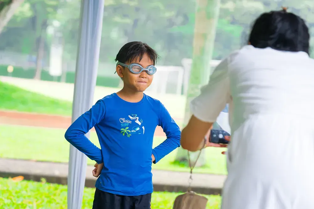 A woman is taking a picture of a young boy wearing goggles.