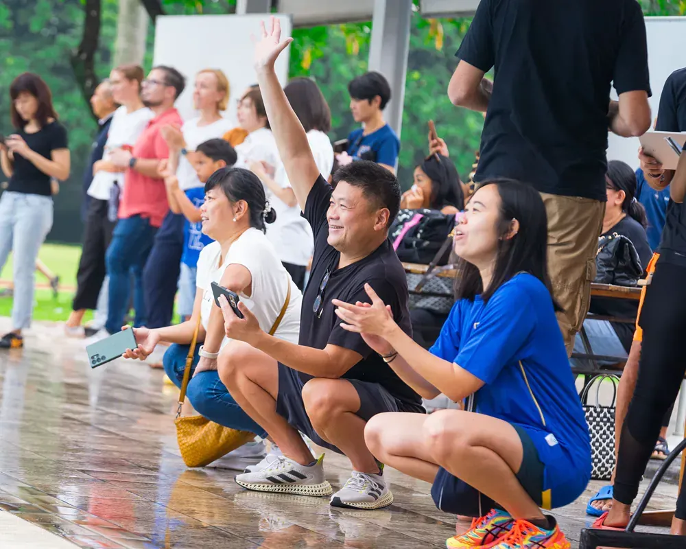 A group of people are sitting on the ground watching a game.