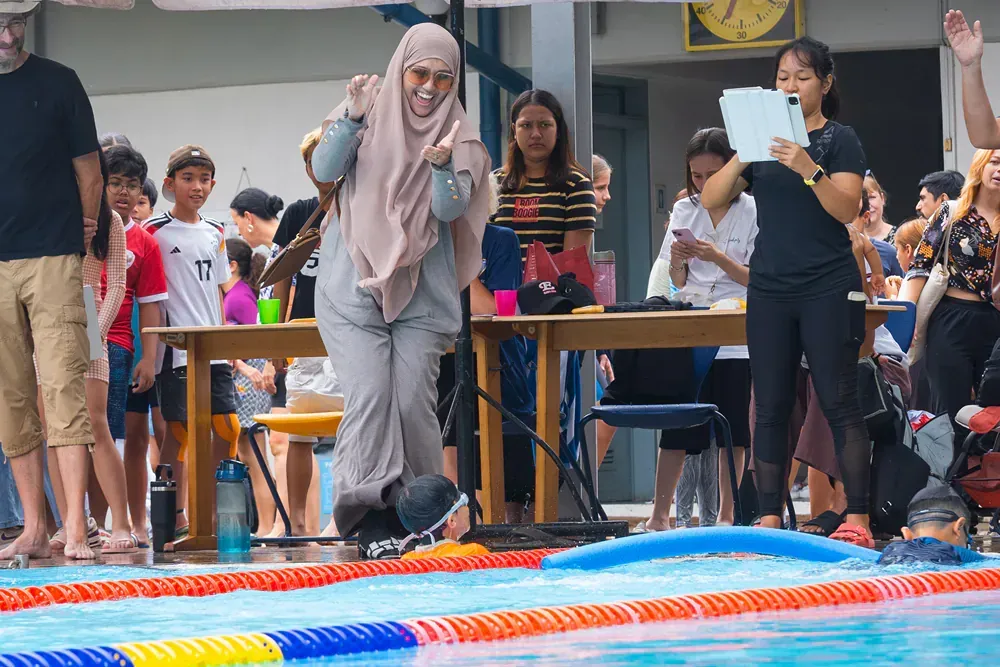 A group of people are standing around a swimming pool.