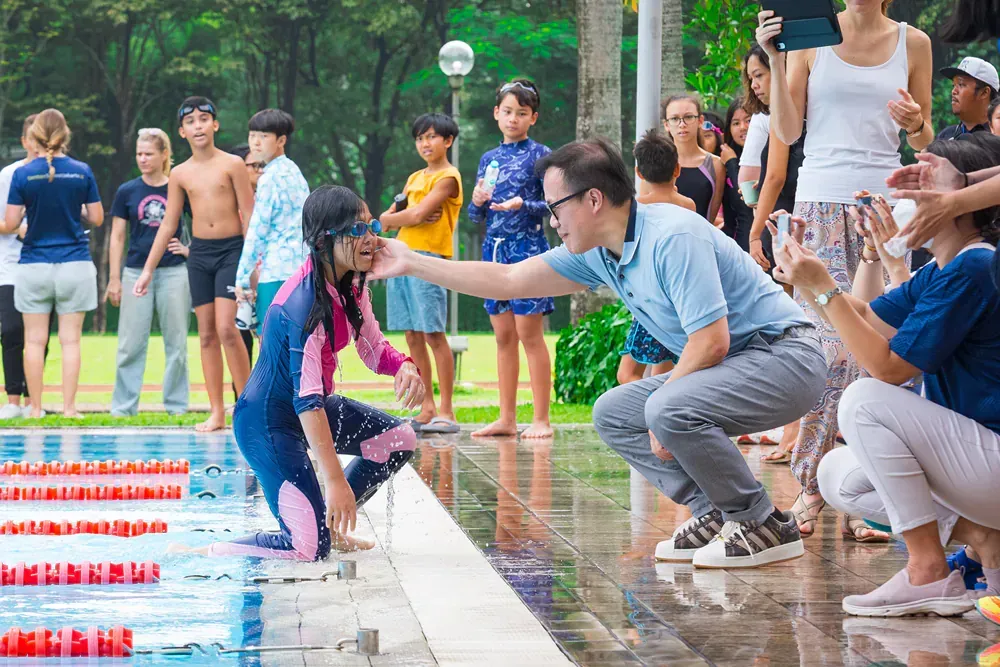 A group of people are standing around a swimming pool.