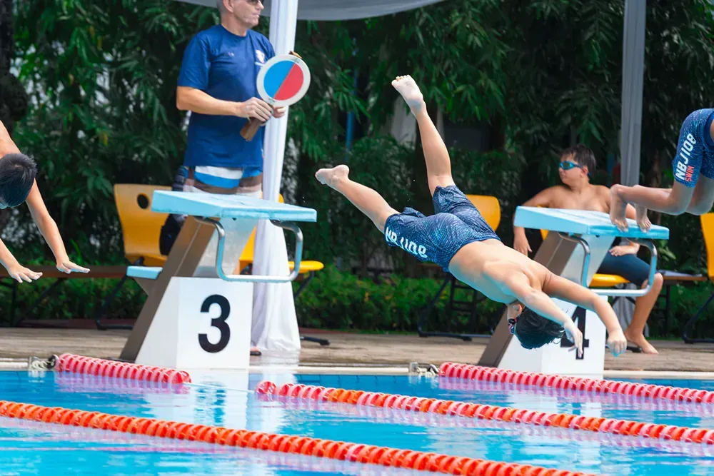 A young boy is diving into a swimming pool.