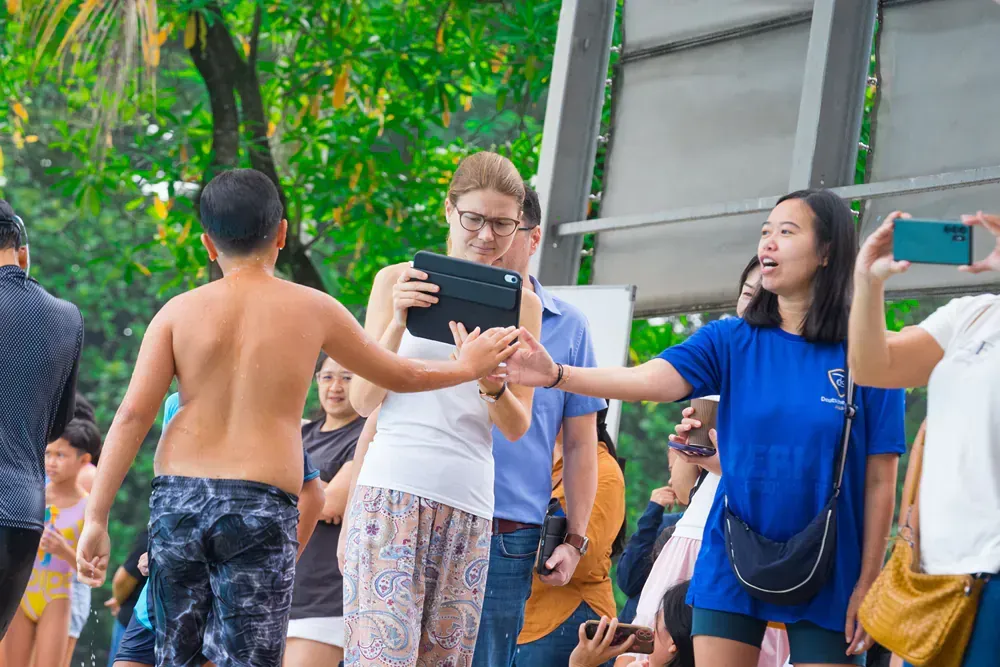 A woman is taking a picture of a boy with a tablet.