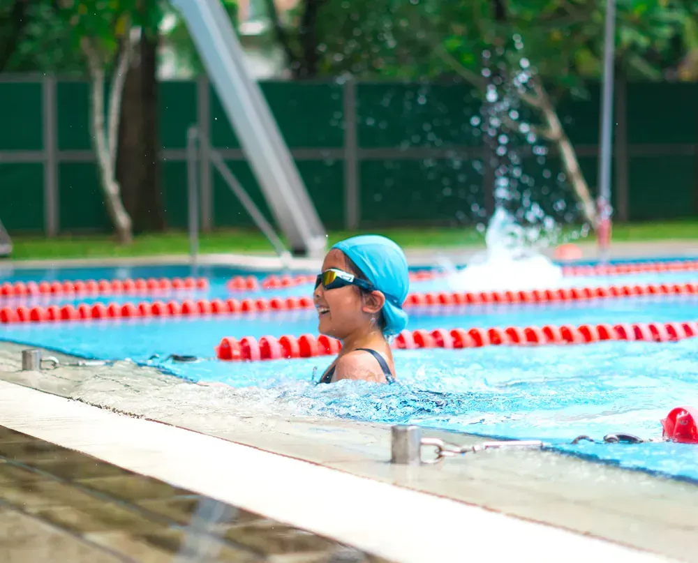 A young girl is swimming in a swimming pool.