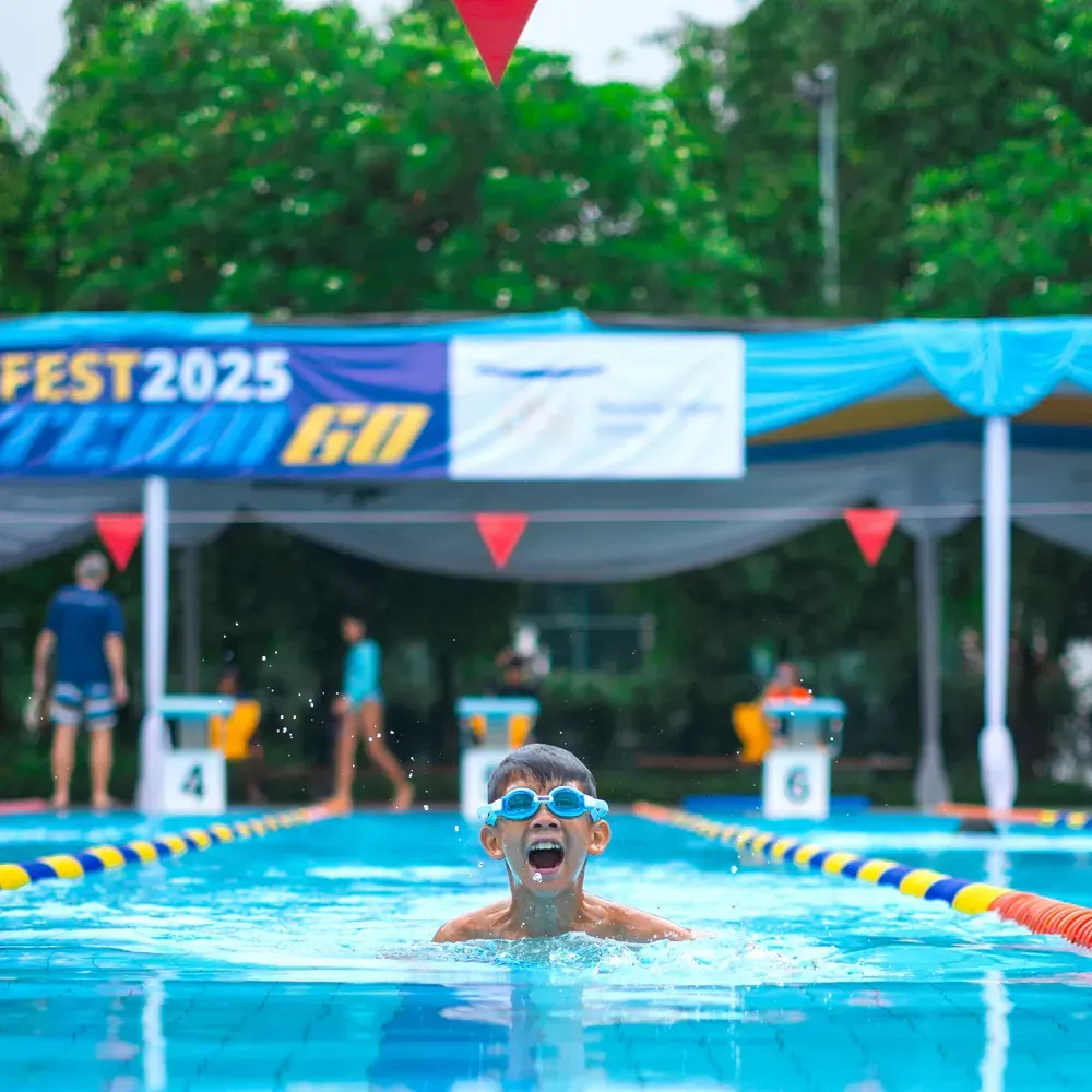 A young boy is swimming in a pool with goggles on.