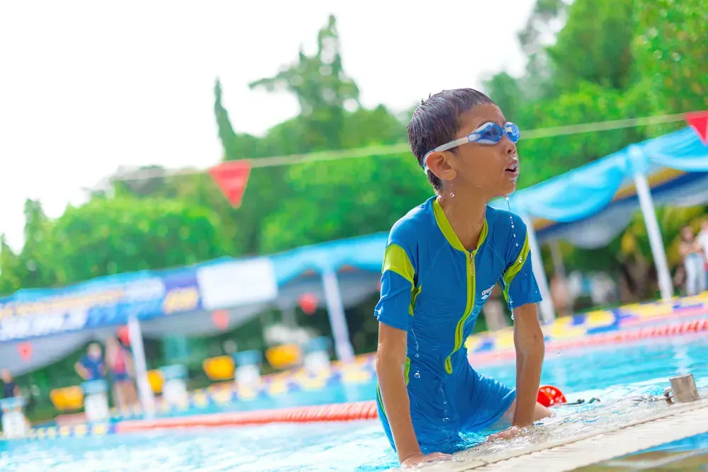 A young boy is sitting on the edge of a swimming pool.