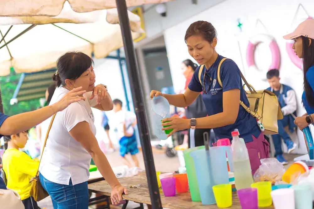 A woman is pouring water into a cup for a woman.