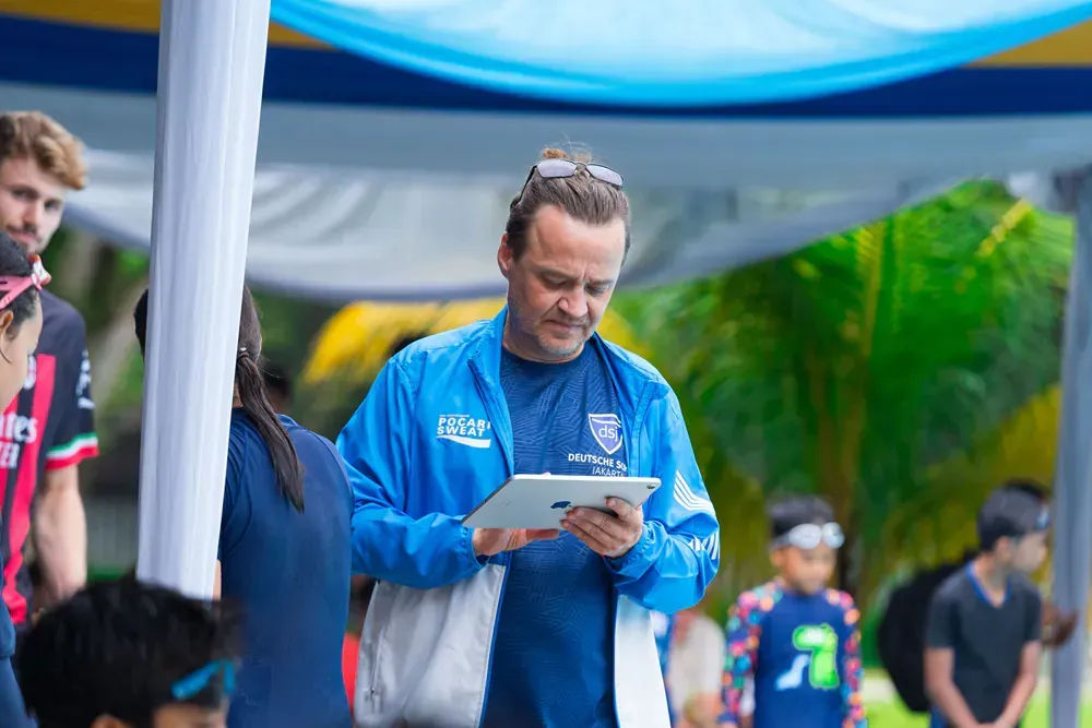 A man in a blue jacket is looking at a tablet.