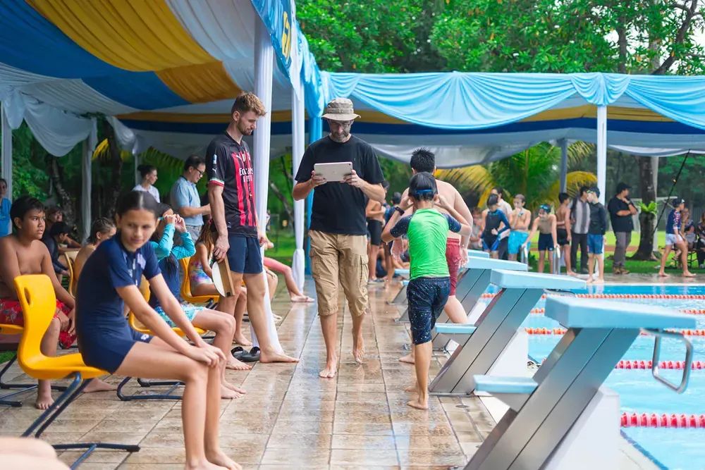 A group of people are standing around a swimming pool.