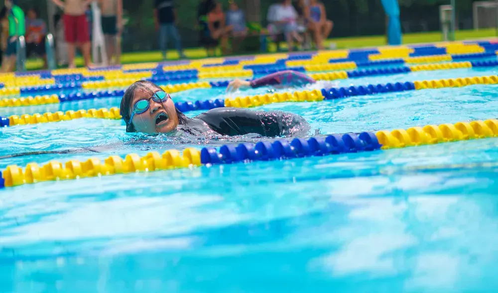 A woman is swimming in a swimming pool.