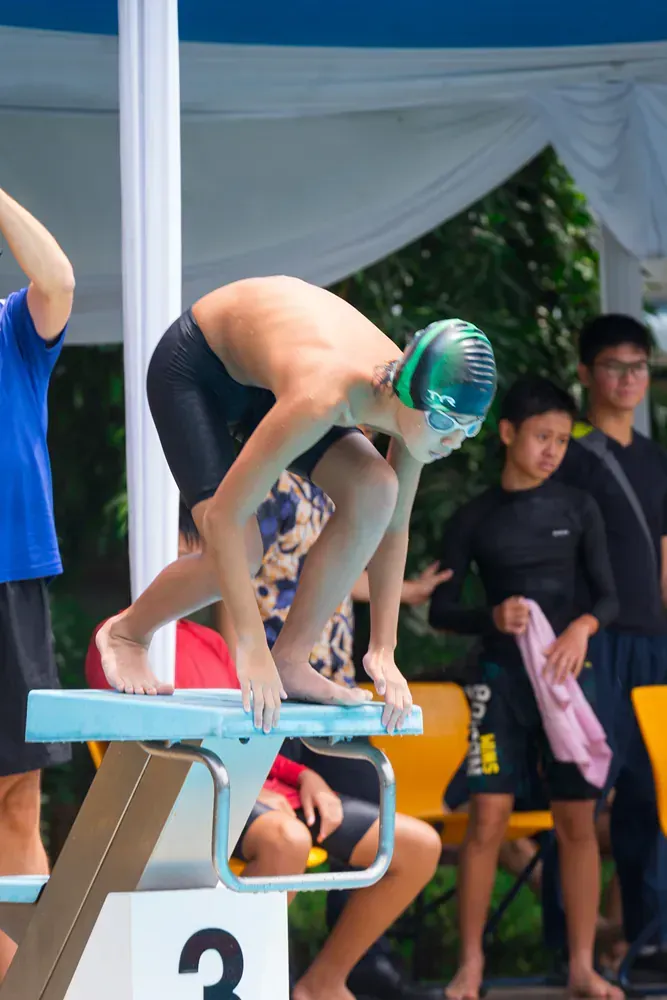 A young boy is getting ready to jump into a pool.