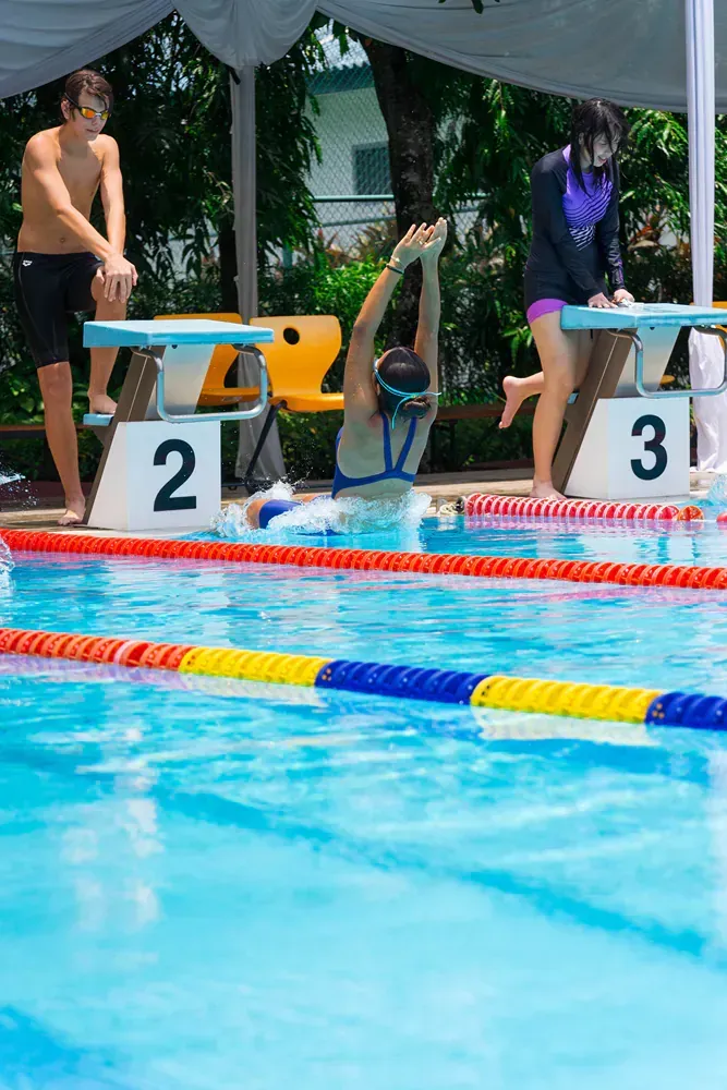 A group of people are swimming in a swimming pool.