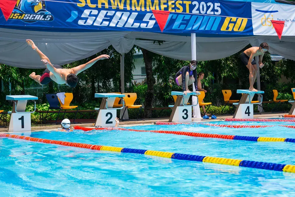 A group of people are jumping into a swimming pool.