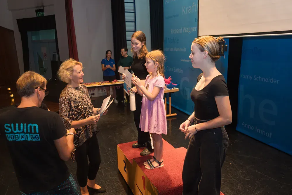 A group of women are standing around a little girl on a podium.