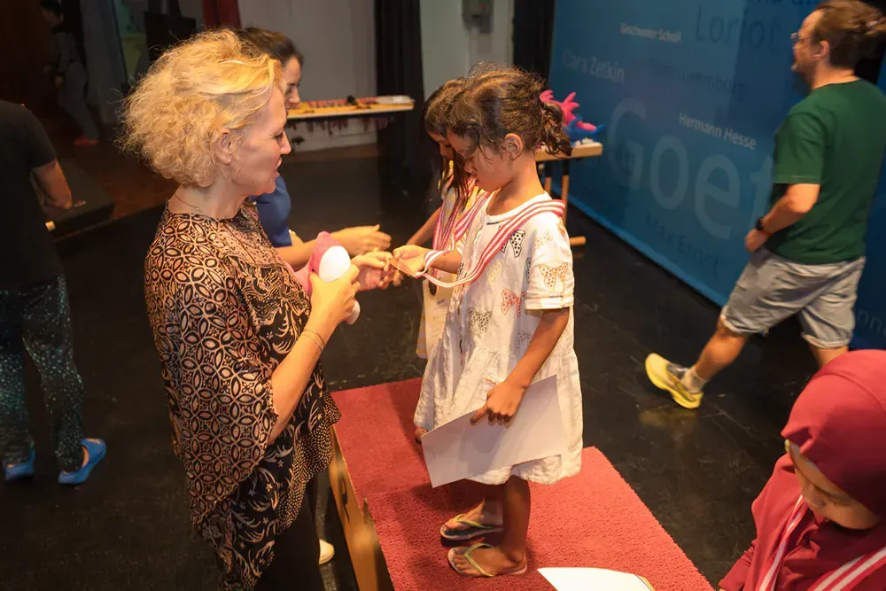 A woman is giving a medal to a little girl