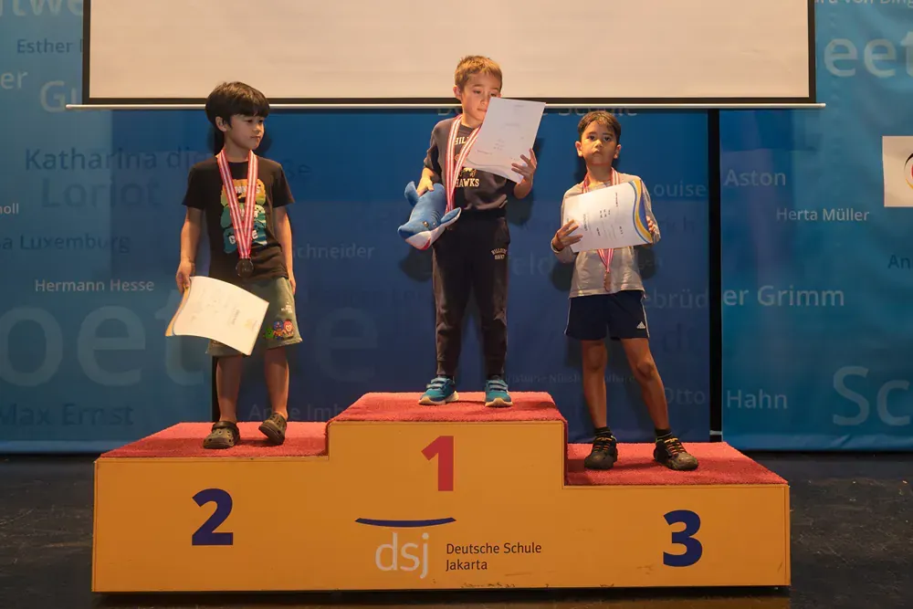 Three children are standing on a podium with the number 1 2 and 3 on it