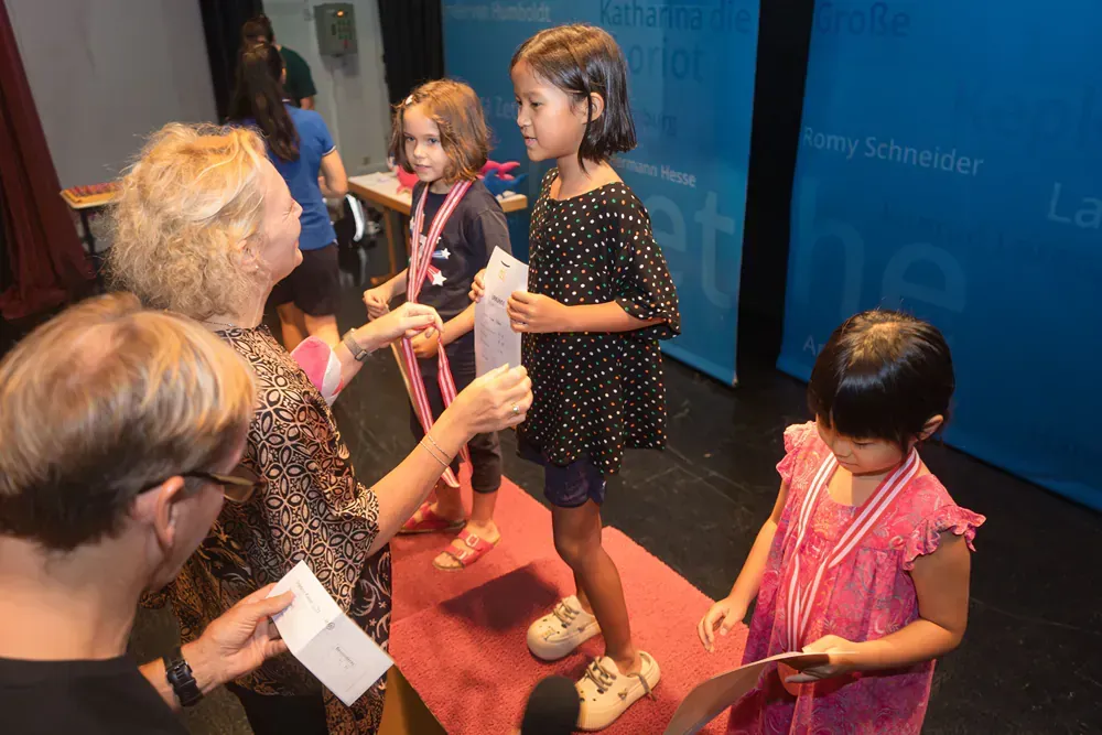 A group of young girls are standing on a stage with medals around their necks.